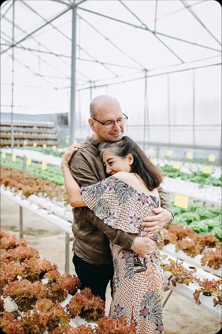 older couple hugging in a greenhouse