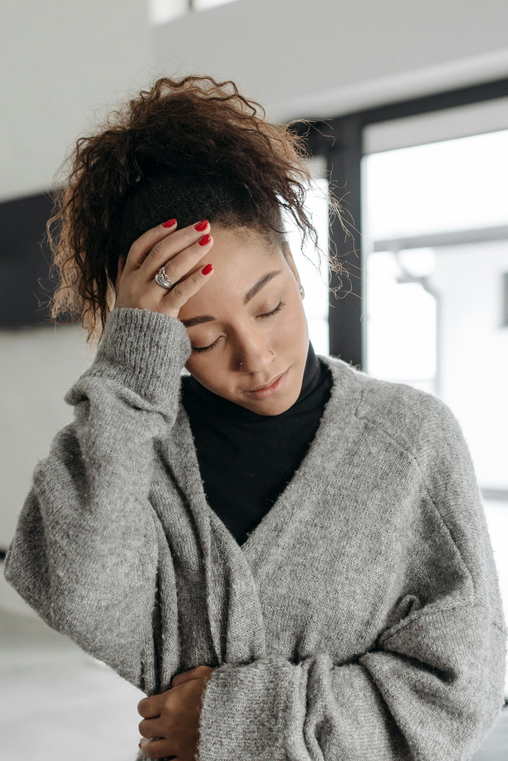 A dizzy Woman with Anemia holding her head with her eyes closed