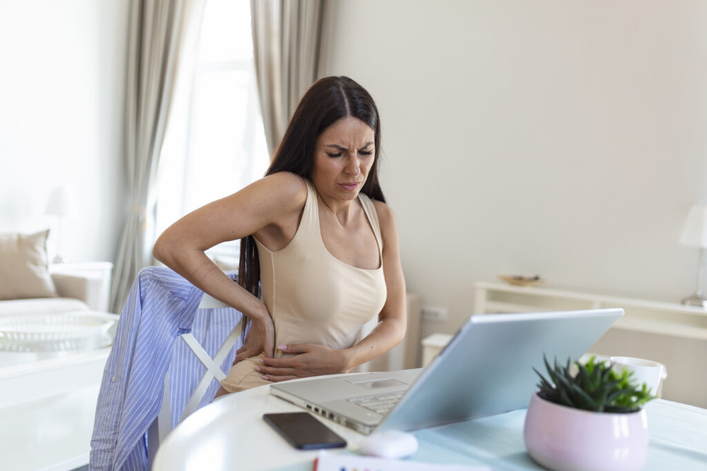 The current image has no alternative text. The file name is: businesswoman-holding-her-back-while-working-laptop-home-office-desk-young-woman-stretching-sitting-feeling-her-back-tired-after-working-laptop-small-home-office-interior-scaled.jpg
