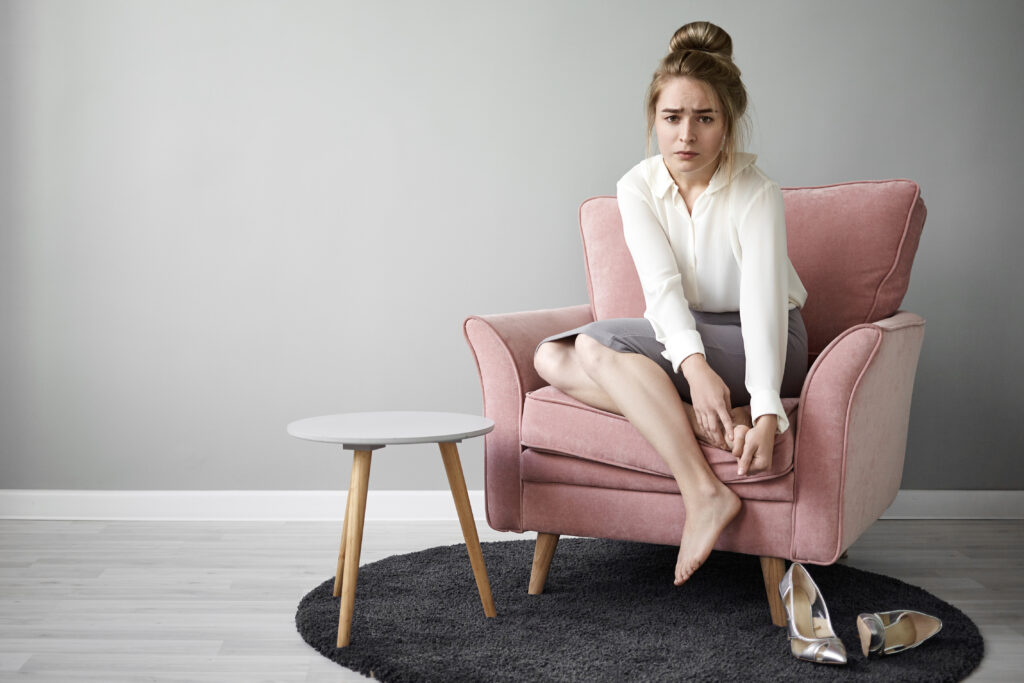 The current image has no alternative text. The file name is: modern-hardworking-young-female-feeling-tired-after-long-walk-high-heeled-shoes-sitting-barefooted-armchair-massaging-her-feet-having-painful-frustrated-facial-expression-health-wellness-scaled.jpg