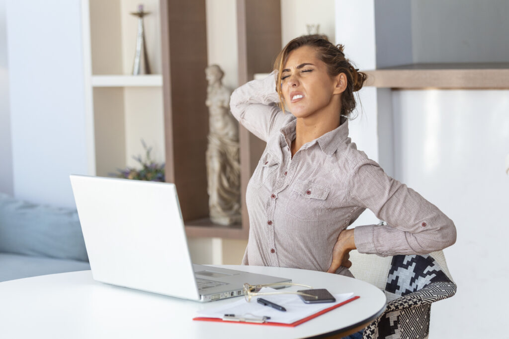 The current image has no alternative text. The file name is: portrait-young-stressed-woman-sitting-home-office-desk-front-laptop-touching-aching-back-with-pained-expression-suffering-from-backache-after-working-laptop-scaled.jpg